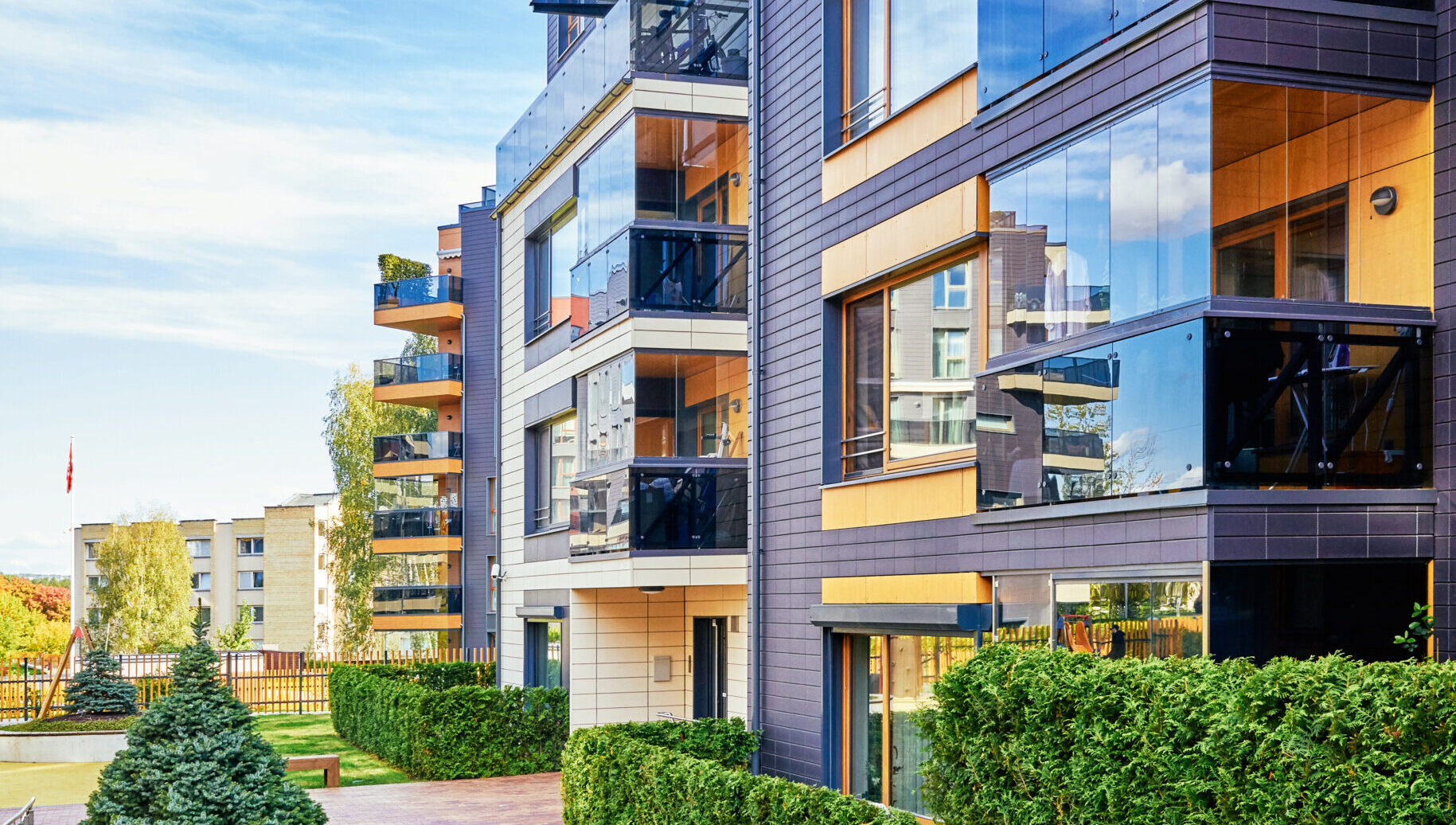 Modern complex of apartment residential buildings with green trees and outdoor facilities.