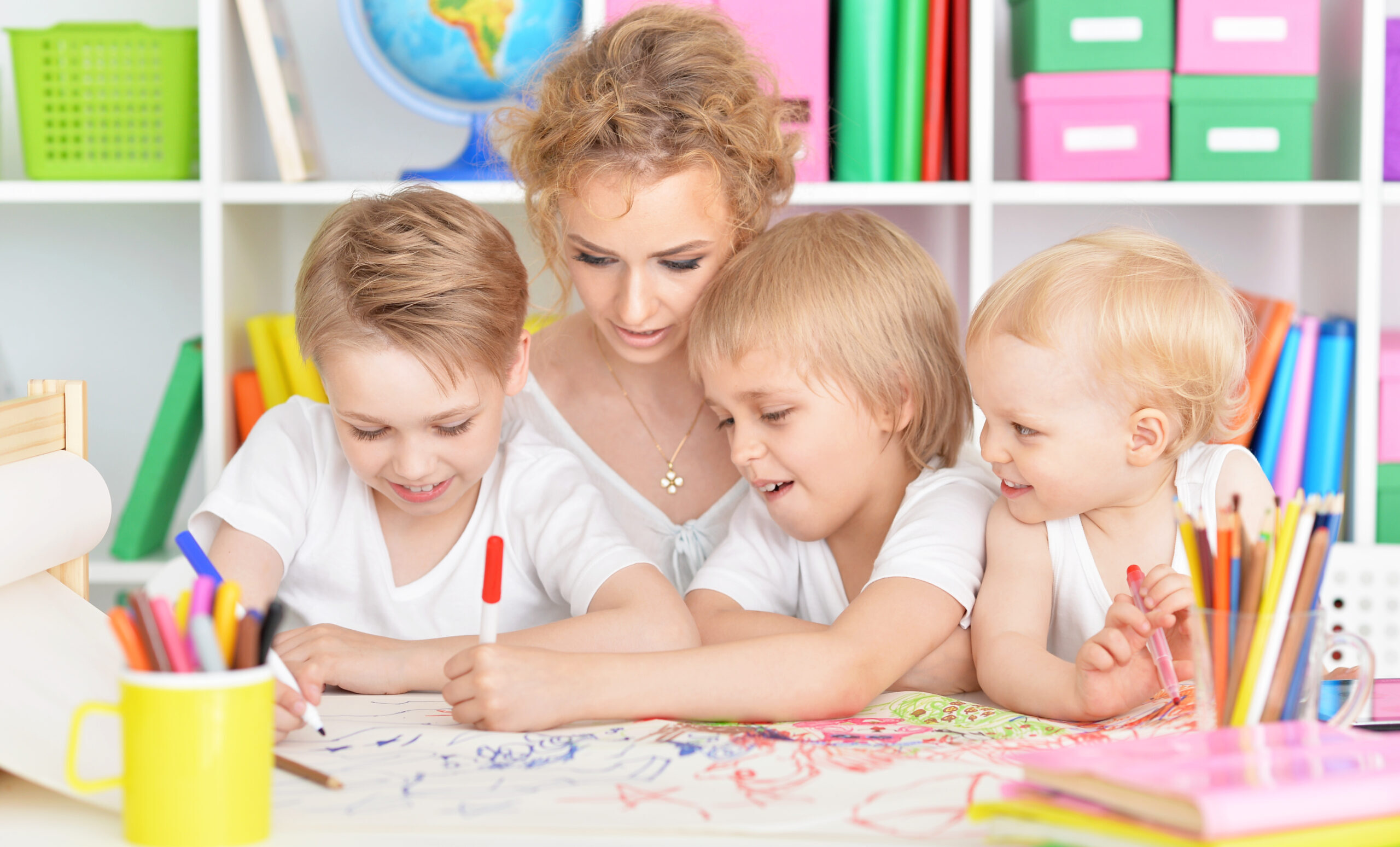 Portrait of happy mother drawing with three cute sons